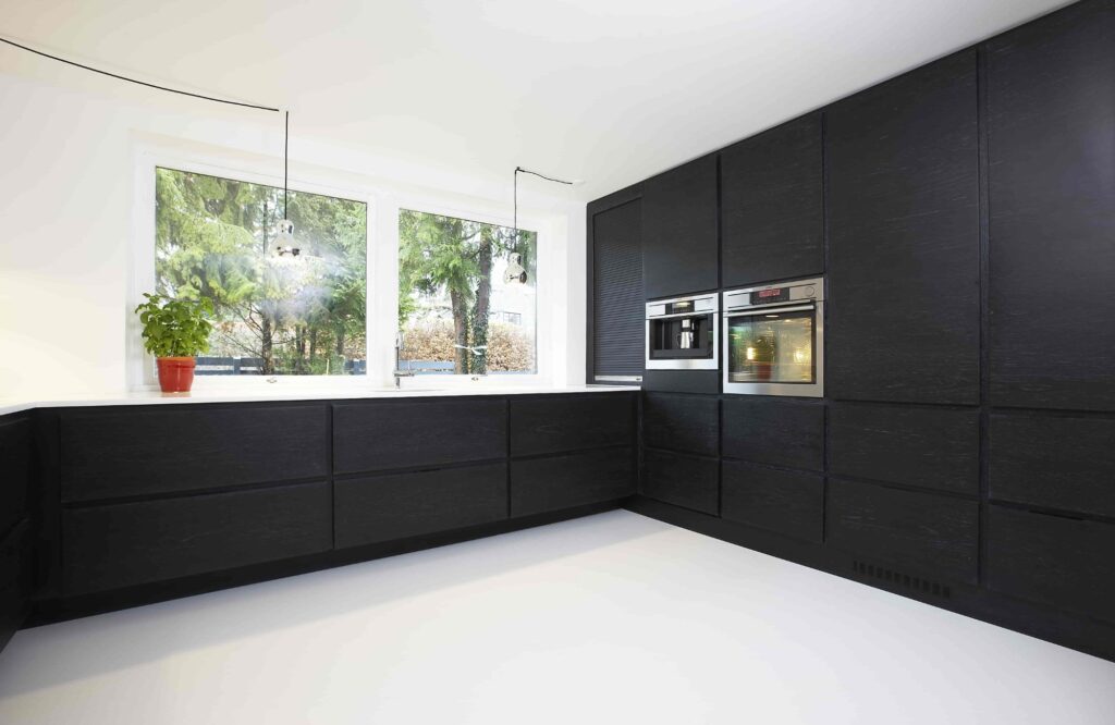 Black L shaped kitchen with white worktop and tall cabinet wall in the Engvej kitchen project, custom made by Venci