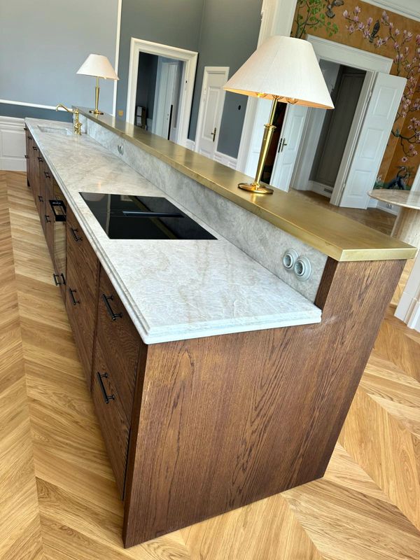 Smoked oak kitchen island with brass bar top and natural stone