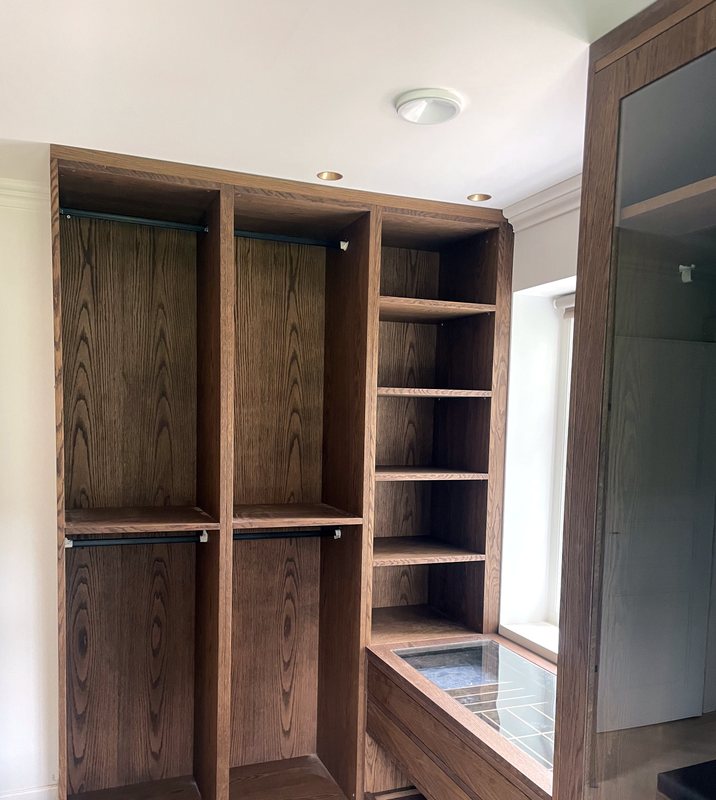 Walk-in wardrobe with hanging sections, shelves and a jewellery drawer in oak